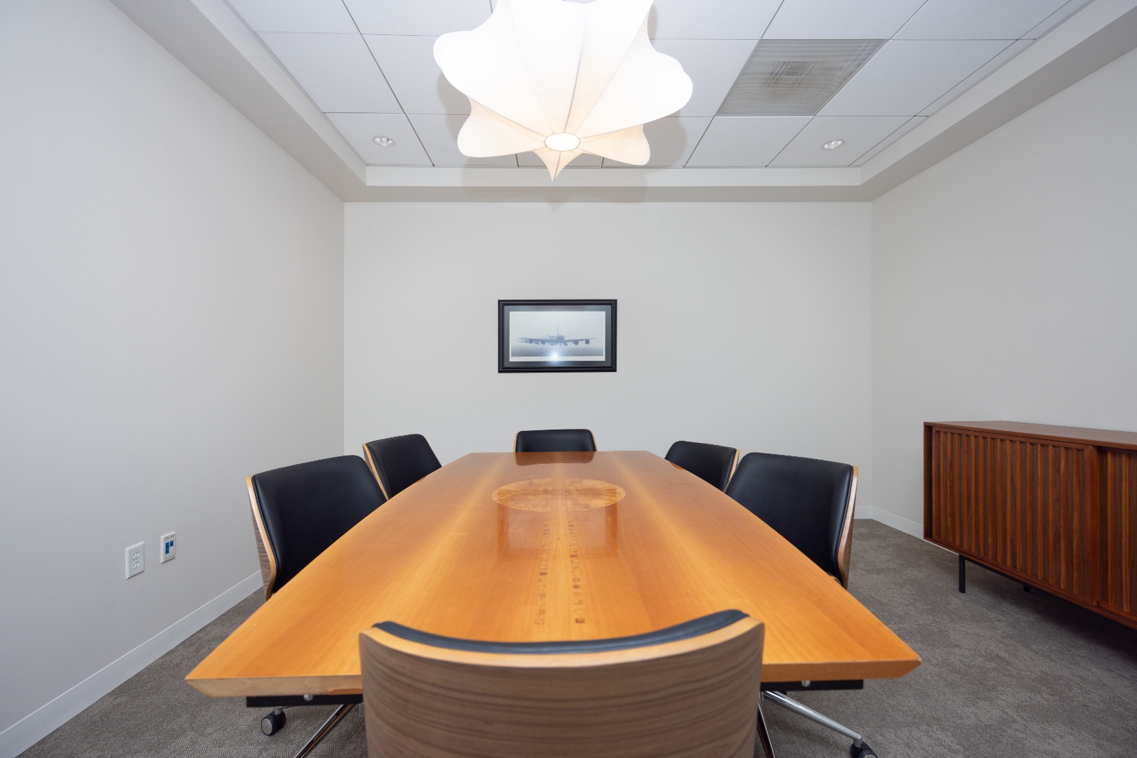 Conference room SR-71 with custom wood table and pendant light at Soaring Suites