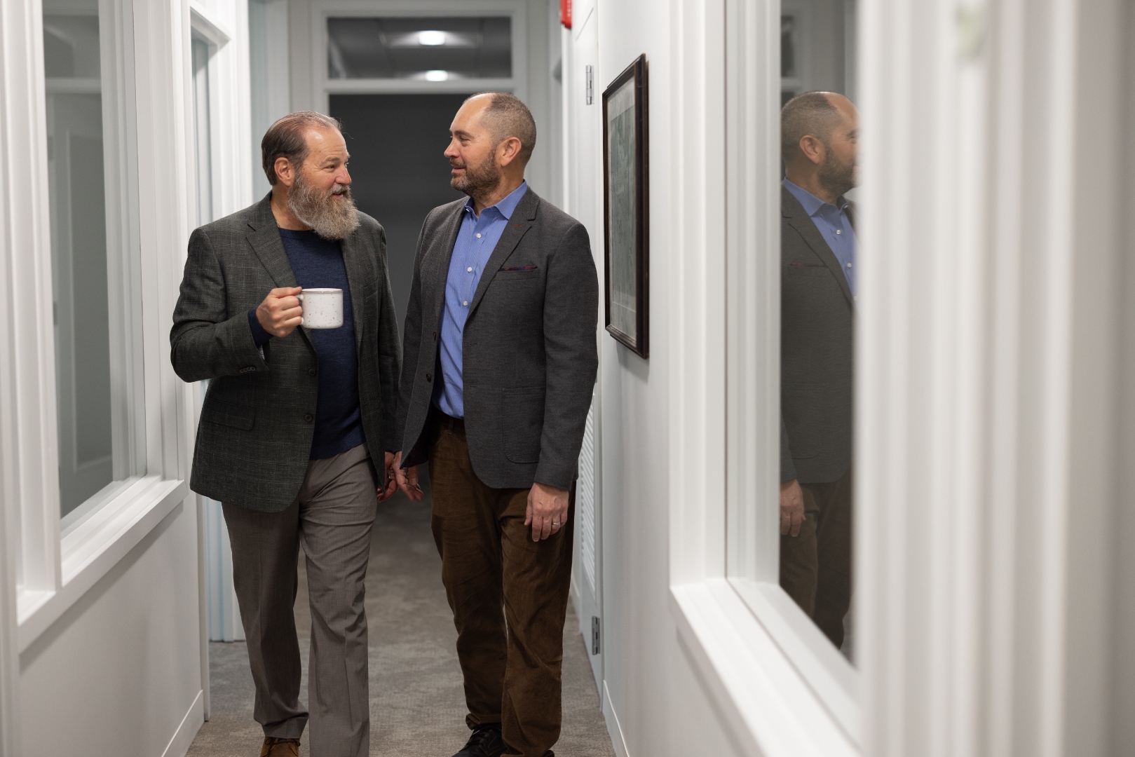 Colleagues chatting over coffee in the hallway at Soaring Suites
